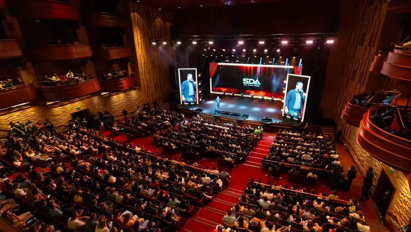 Plateia lotada em evento da SDA, com palco e telões ao fundo